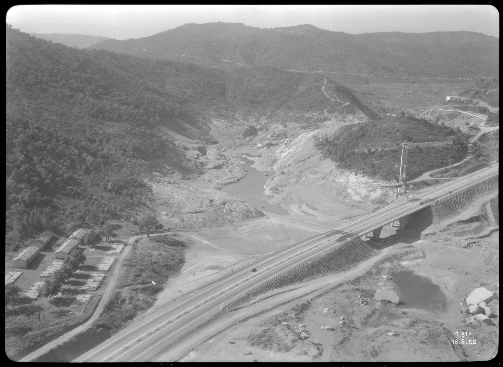 Vue aérienne de la zone du barrage de Malpasset en arrière fond, de l'autoroute, du pont et du hameau de forestage