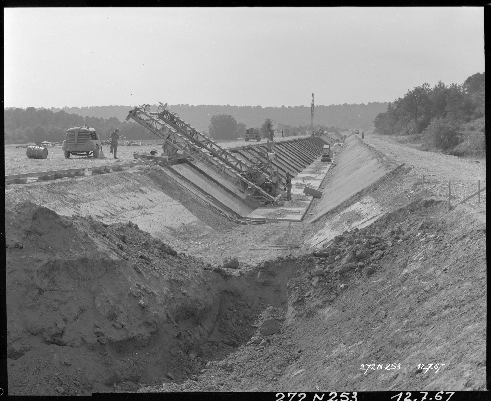 Construction du canal, pose du revêtement sur un côté du canal, ouvriers, machines, grue au fond