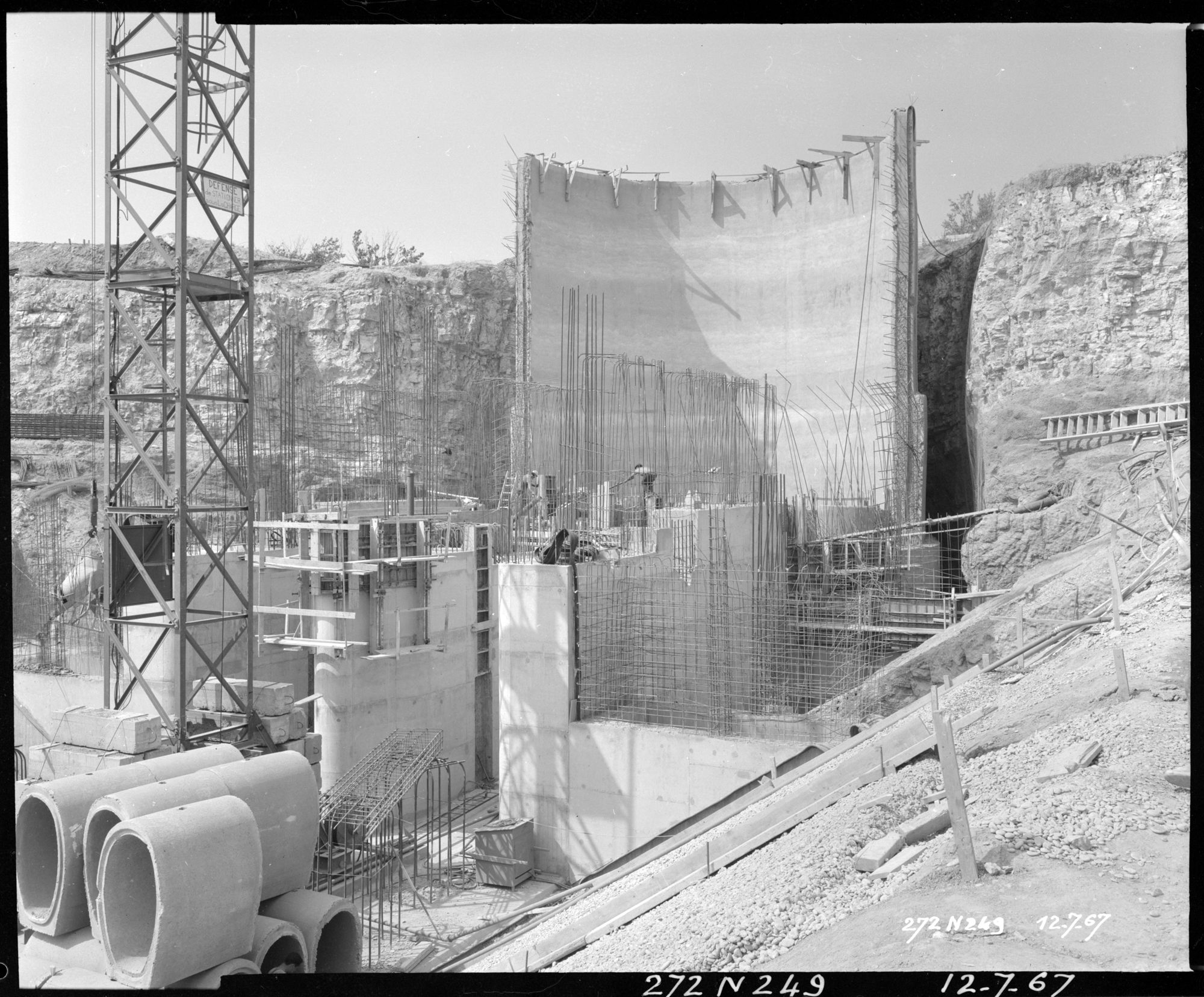 Construction d'un grand mur arrondi, pied d'une grue, ouvriers, ferraille, béton