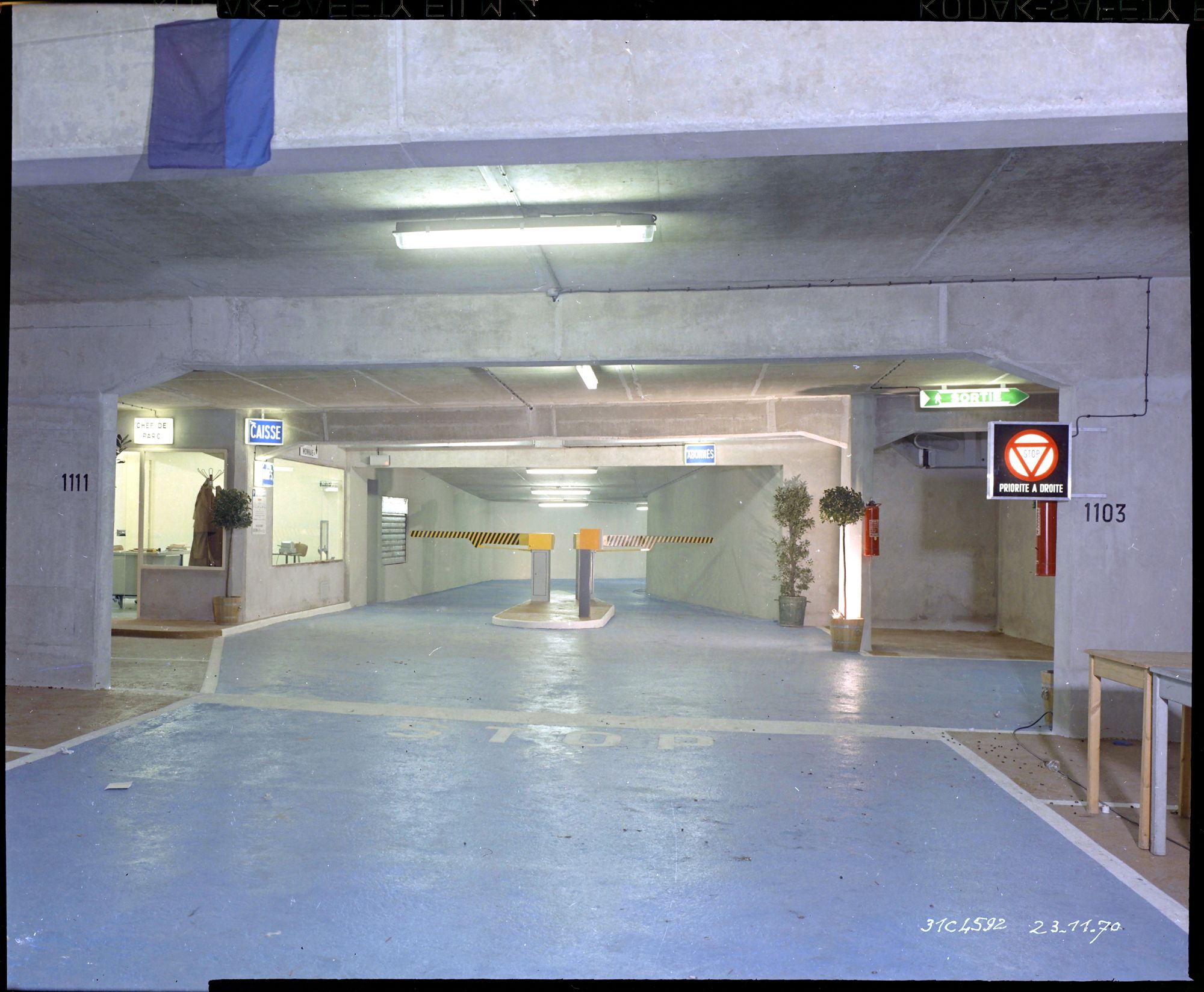 Vue de la sortie véhicule au sous-sol du parking souterrain terminé, barrières, caisse et bureau du chef du parc